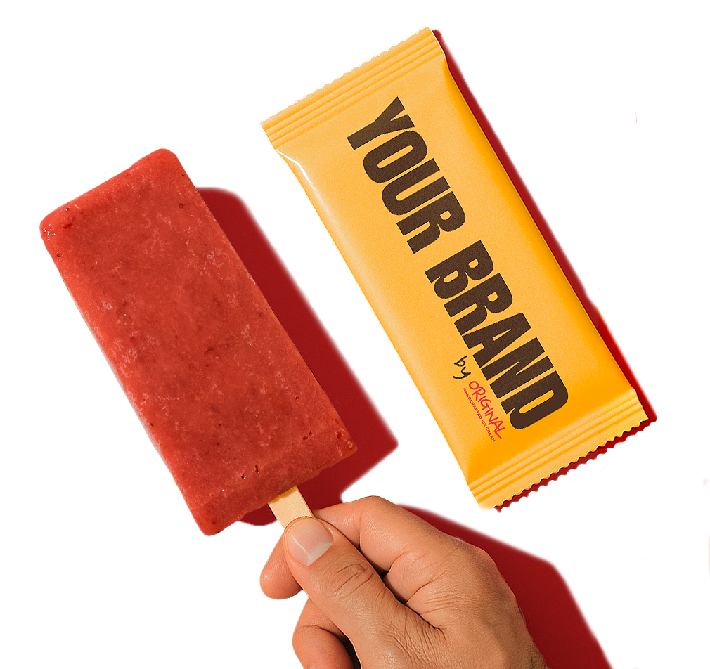 A close-up promotional image of a strawberry-colored ice cream bar held by a hand against a vivid red background. Beside it, a bright yellow wrapper is placed diagonally, featuring bold black text reading “YOUR BRAND” with a small “by Original” mark underneath. Strong directional lighting creates defined shadows and gives the composition a modern, colorful advertising look.